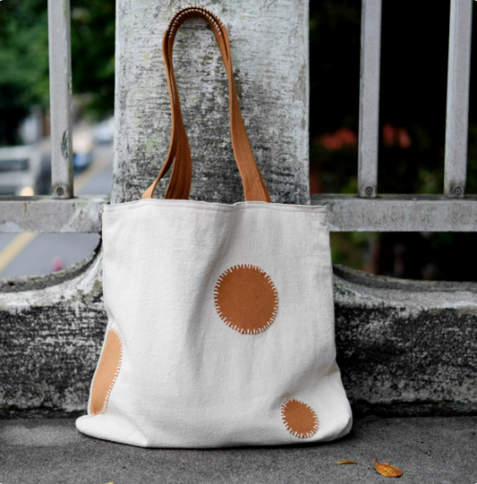 A person carrying a colorful patchwork canvas tote made from recycled fabric remnants.