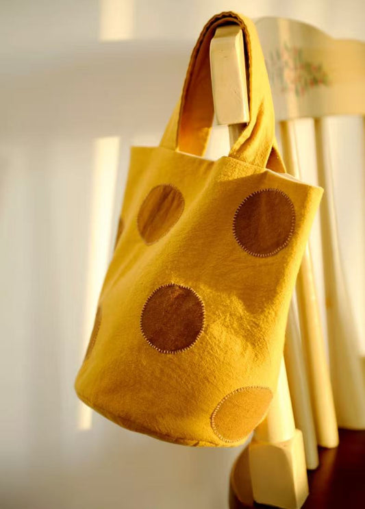 Someone carrying a heavy load of books and fresh produce in a sturdy cream canvas bag.