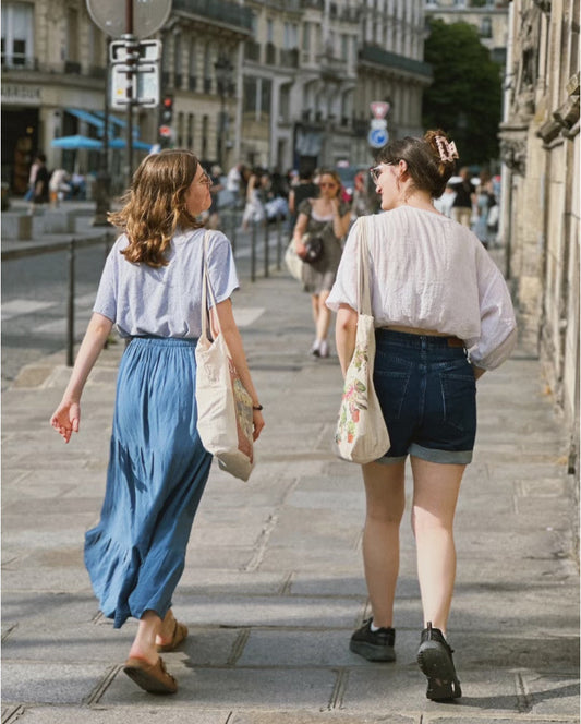 A person wearing a casual dress carrying a canvas tote bag over their shoulder during a grocery run.