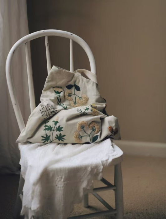 Lifestyle image of a hand-embroidered patchwork tote being used at a local farmers market.