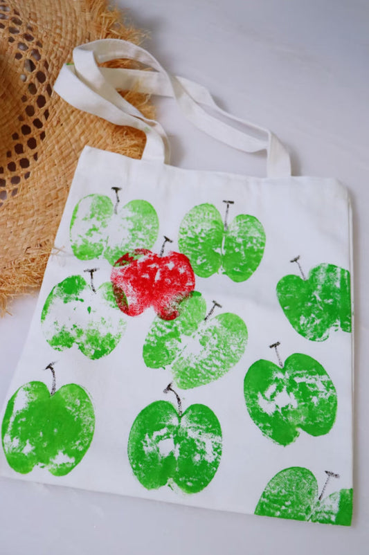 A person carrying a mid-size canvas shoulder bag filled with a laptop and water bottle.