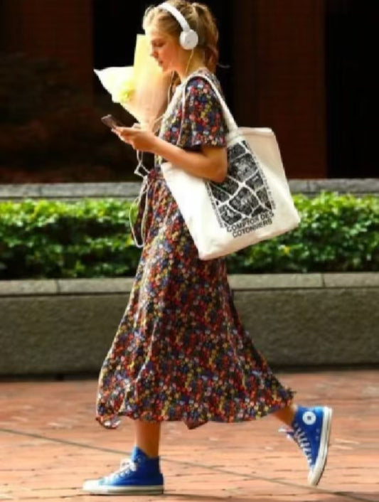 Embroidered cotton tote bag with unique patchwork design, folded neatly on a cafe chair