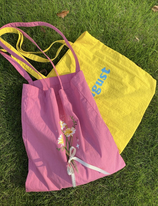 A fabric tote bag in use, carrying groceries, a novel, and a lunchbox, showing its durability and practical use.