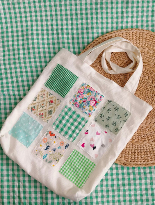 Hand-stitched patchwork fabric bag displayed with notebook and keys, showcasing unique artisan details