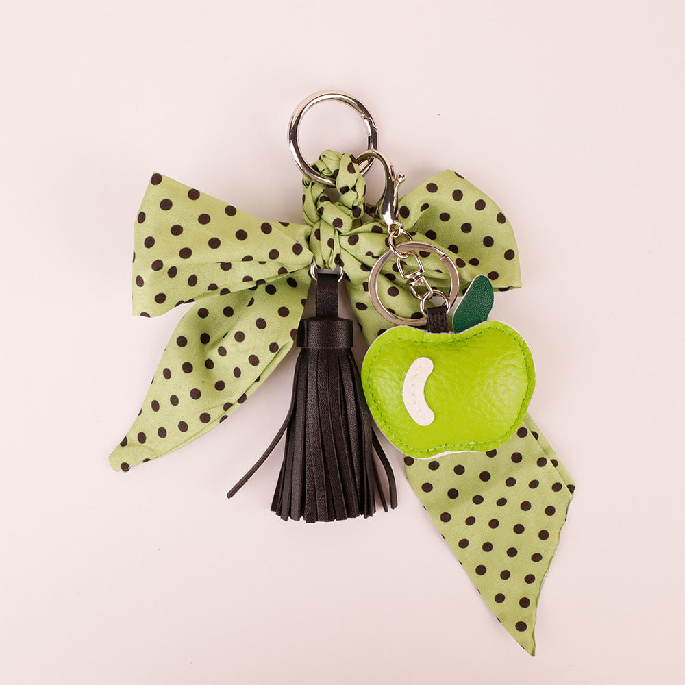 Aesthetic dark green bow key charm resting on wooden surface