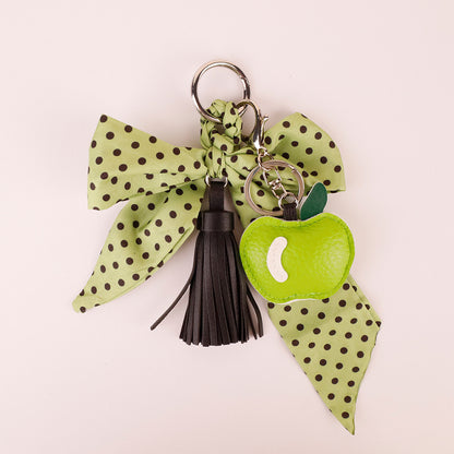 Aesthetic dark green bow key charm resting on wooden surface