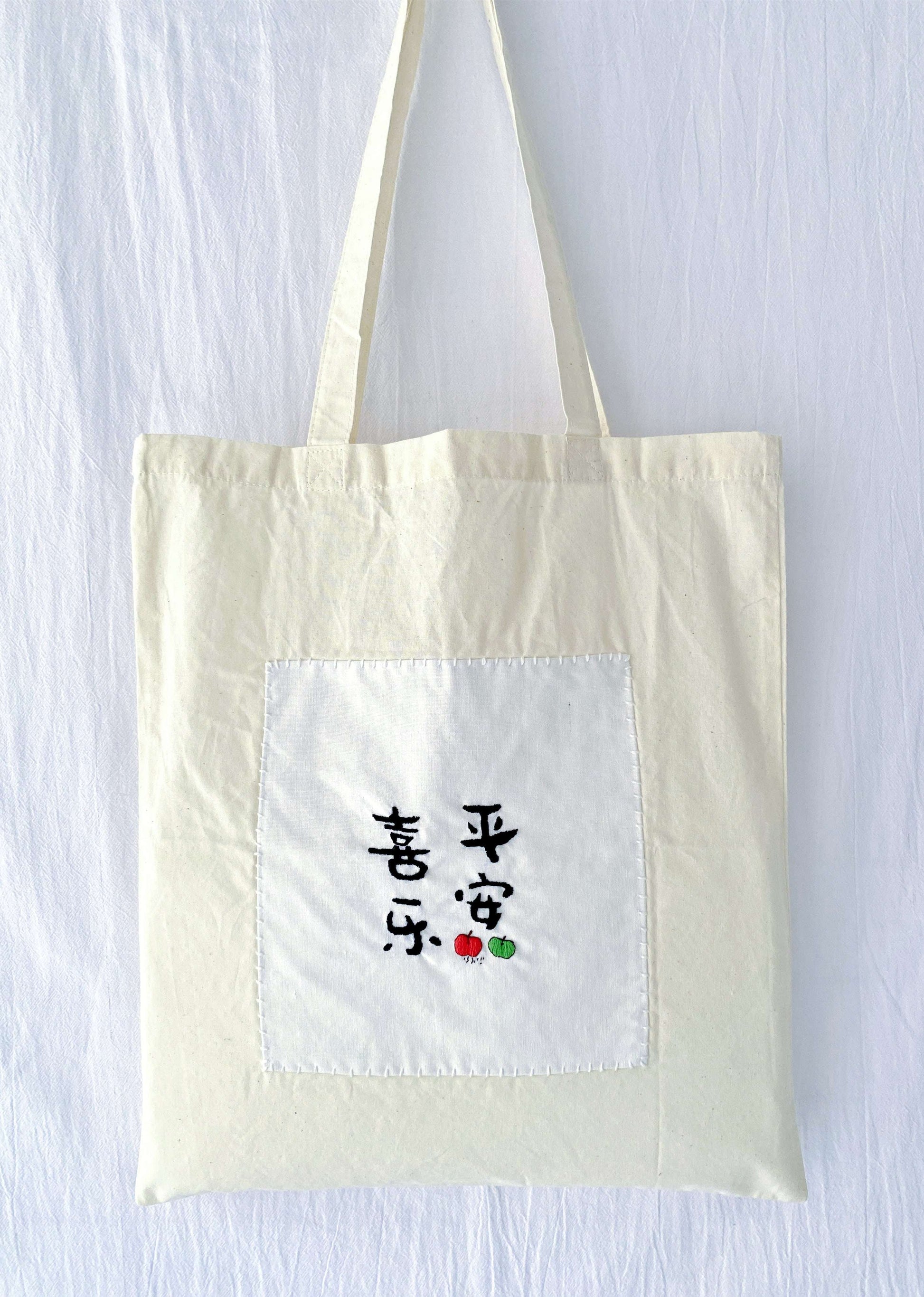 Soft organic cotton tote featuring hand-stitched Chinese calligraphy, a sustainable choice for plastic-free market days.