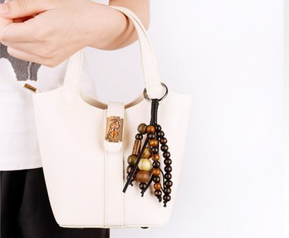 Seed and bead charm clipped to a leather handbag