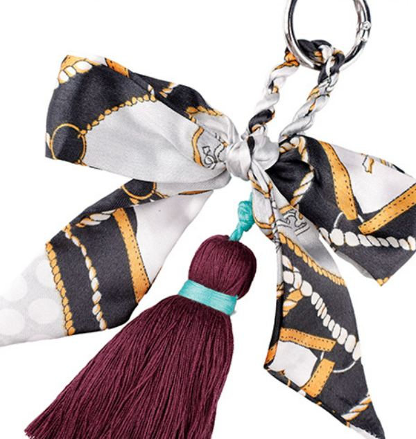Handmade ribbon bag tassel hanging from a summer straw tote