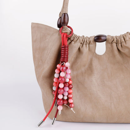 Hand-strung bead piece displayed on a shoulder bag
