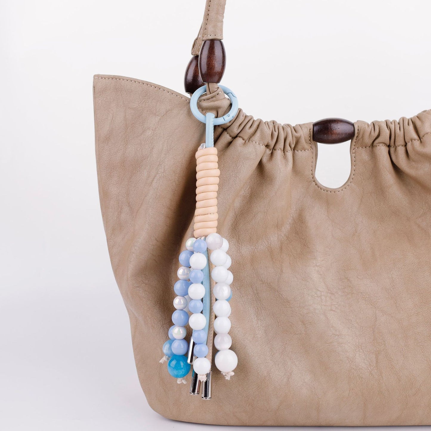 Green beaded charm hanging from a leather handbag