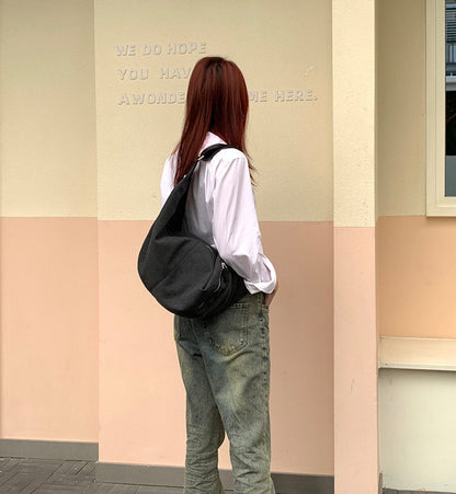 Women's canvas sling bag worn with a relaxed everyday outfit