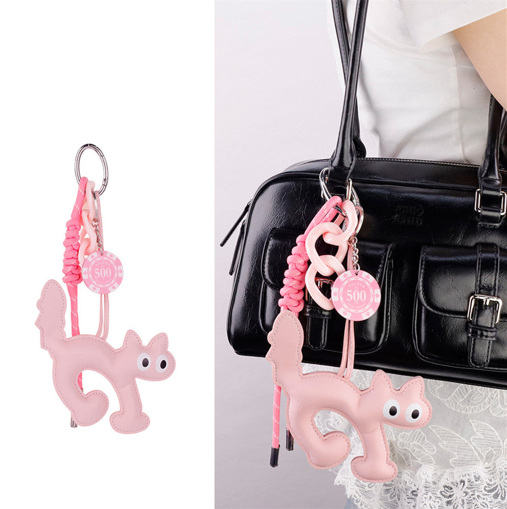 Cute resin cat pendant hanging from the strap of a crossbody purse