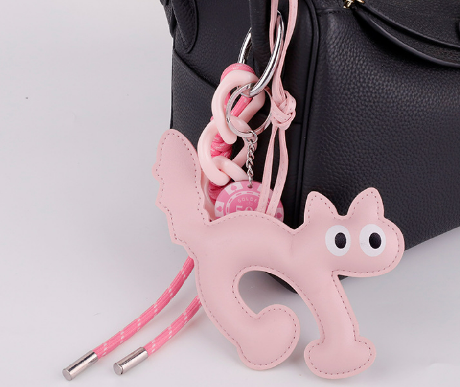 Playful cat keychain placed next to a wrapped birthday gift box