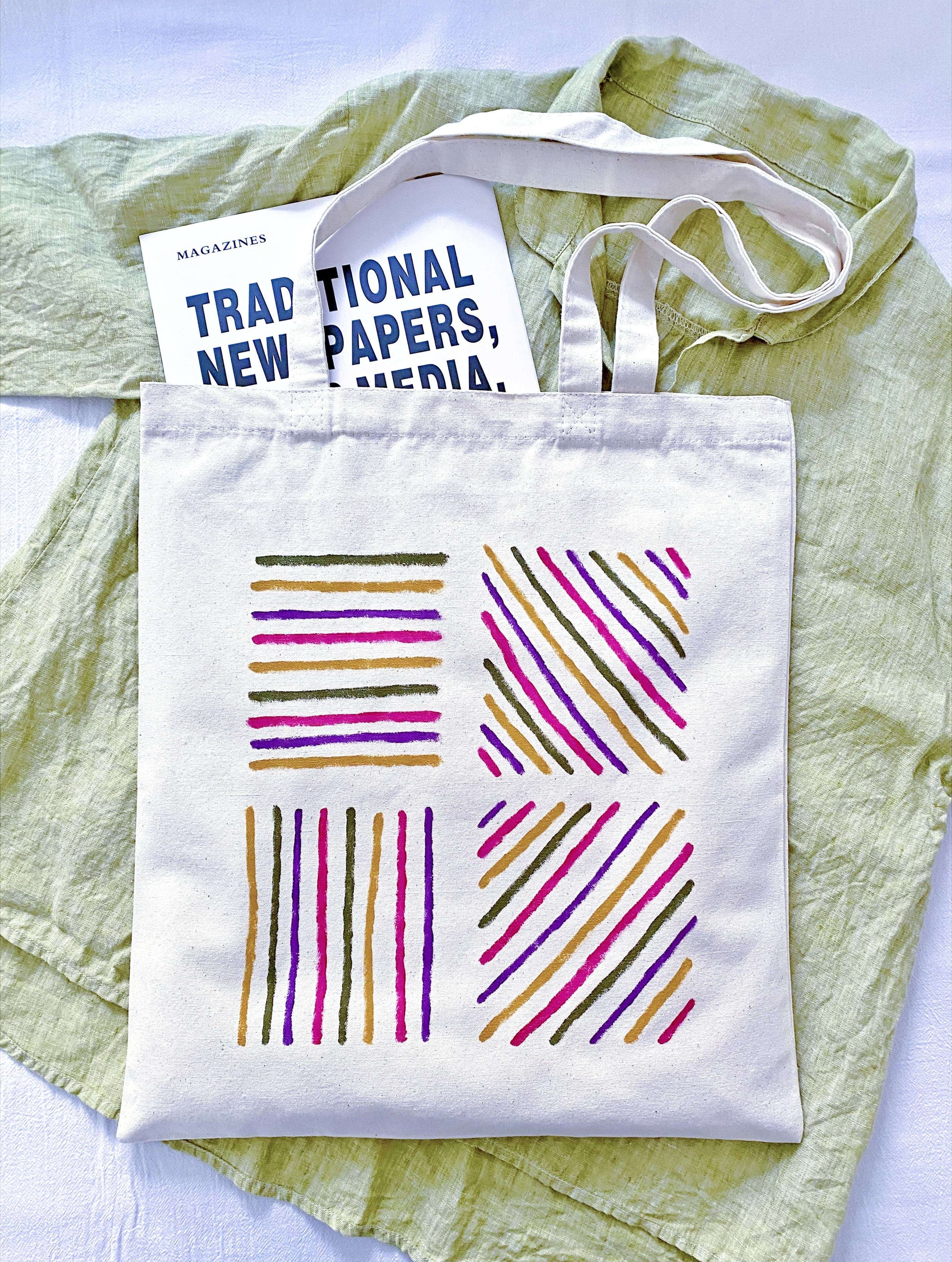 A person hanging a slouchy canvas bag on a rustic wooden peg.