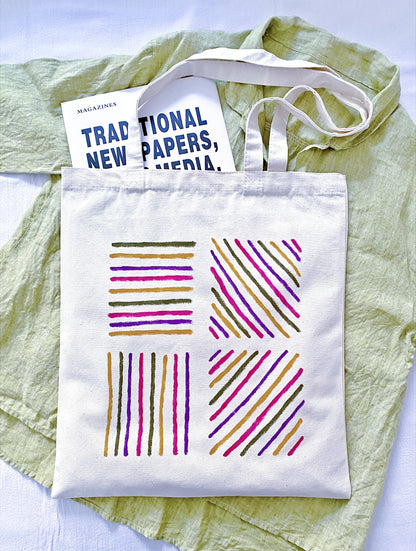 A person hanging a slouchy canvas bag on a rustic wooden peg.