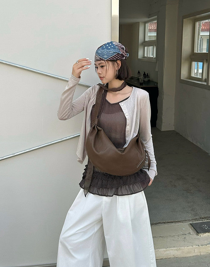 Roomy sling purse worn crossbody during a city stroll.