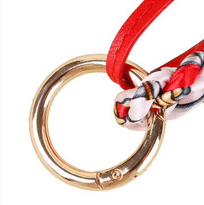 Handmade leather dachshund purse charm dangling from a woven shoulder bag