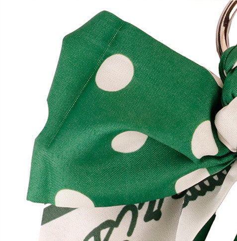 Close up of forest green bow bag accessory on woven straw bag