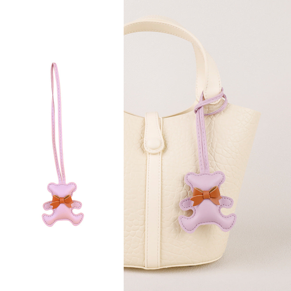 Bear bag charm with silk scarf detail dangling on a minimalist leather bag