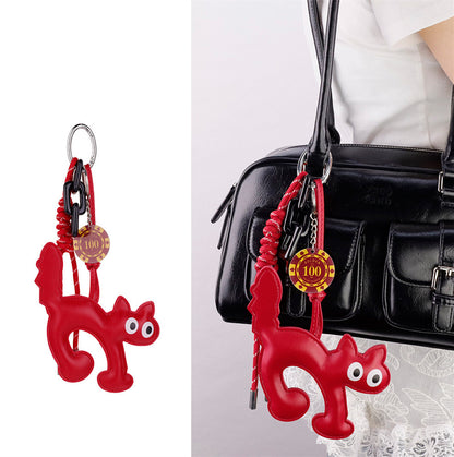 Resin cat charm with hand-woven lanyard attached to a bag zipper pull