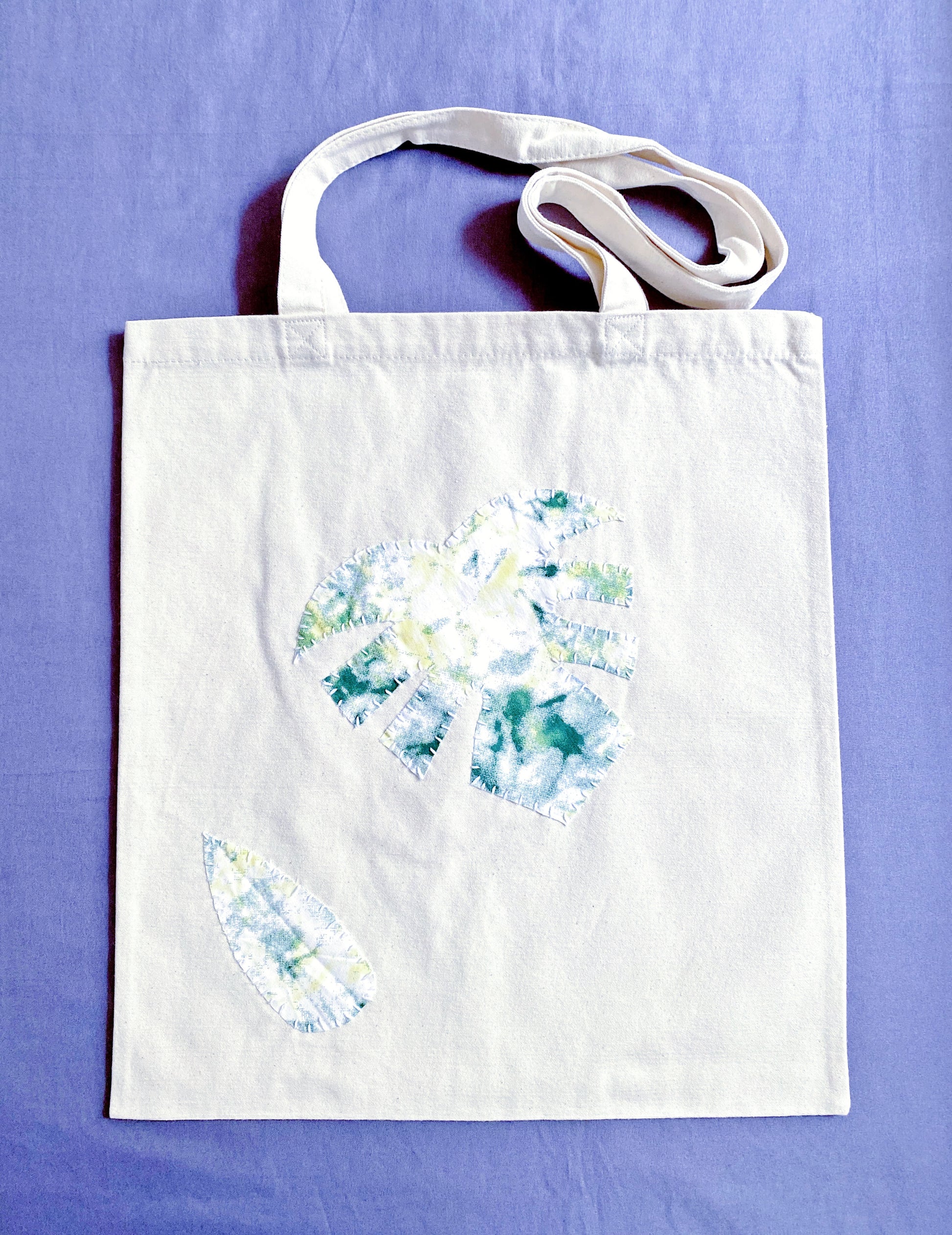 A spacious eco-friendly canvas tote with stitched patchwork, perfect for carrying books during a sunny afternoon walk in Berlin.