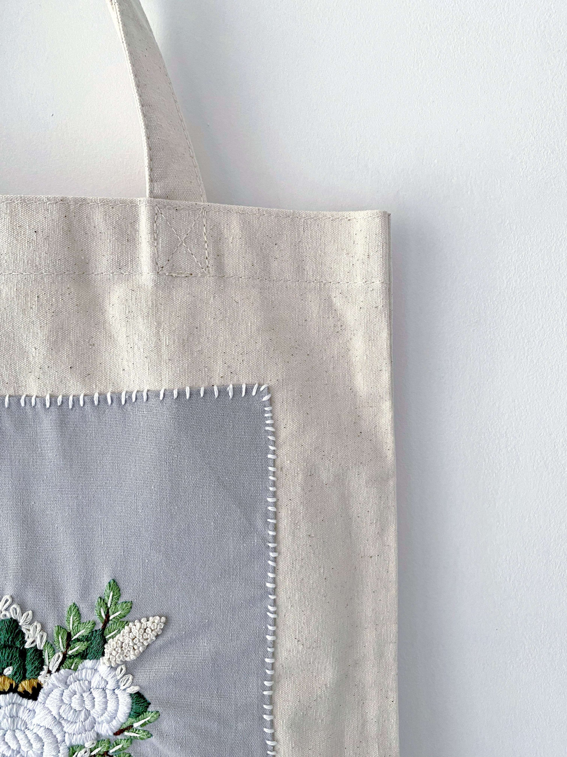 For the friend who has everything but wants nothing plastic; a natural cotton canvas gift that proves utility and high-end embroidery can coexist beautifully.