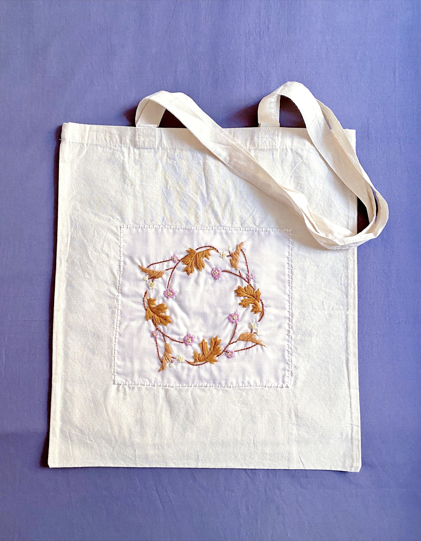 Versatile, eco-friendly cotton tote with hand-stitched flowers, perfect for adding a touch of sustainable elegance to any look.