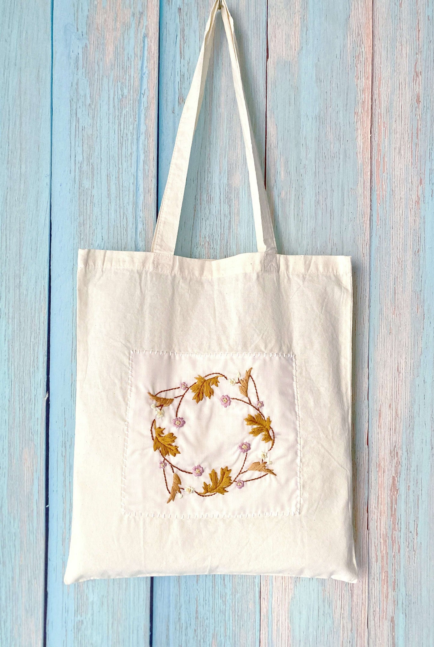 Perfect for the sustainable fashionista, this cotton tote with hand-stitched flowers combines beauty and practicality.