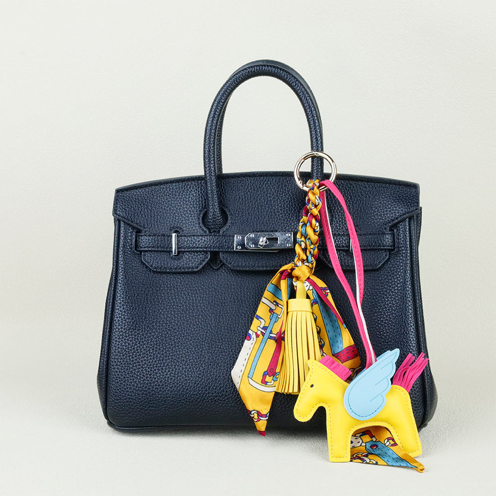 Cognac brown horse bag ornament paired with a modern neutral shoulder bag for daily outfits