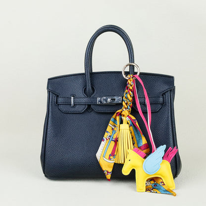 Cognac brown horse bag ornament paired with a modern neutral shoulder bag for daily outfits