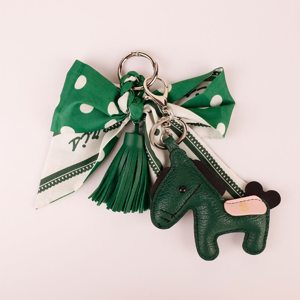 Elegant green ribbon purse accessory hanging on modern leather bag