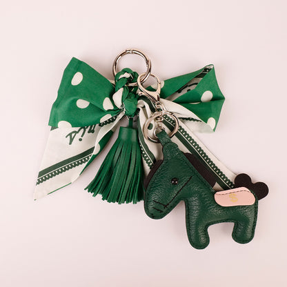 Elegant green ribbon purse accessory hanging on modern leather bag