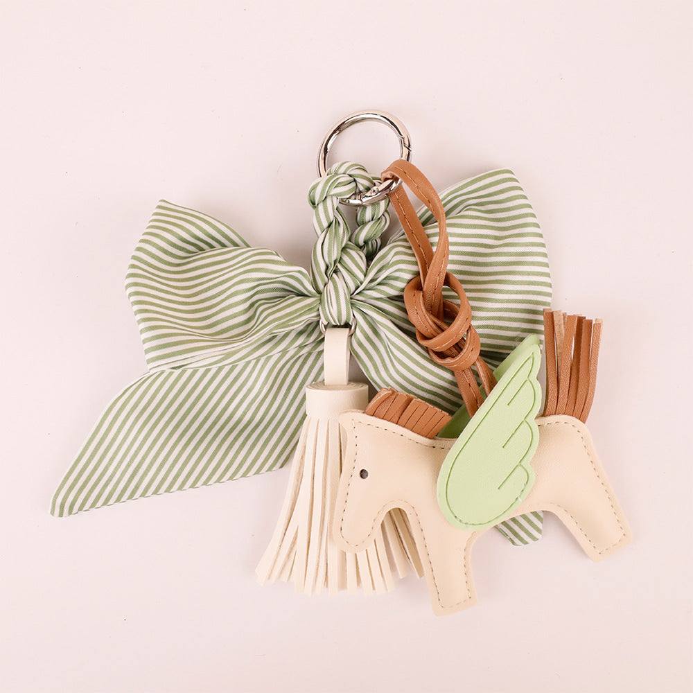 Forest green tassel ribbon keychain held in hand outdoors