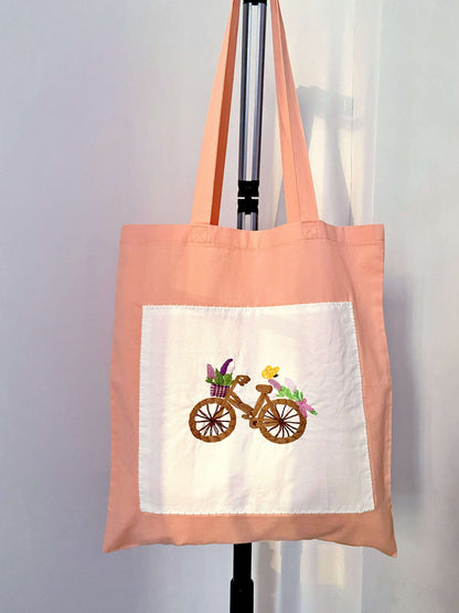 A hand-embroidered sustainable orange tote bag being unwrapped, serving as a thoughtful eco-friendly gift for someone who appreciates slow fashion and artisanal craft.