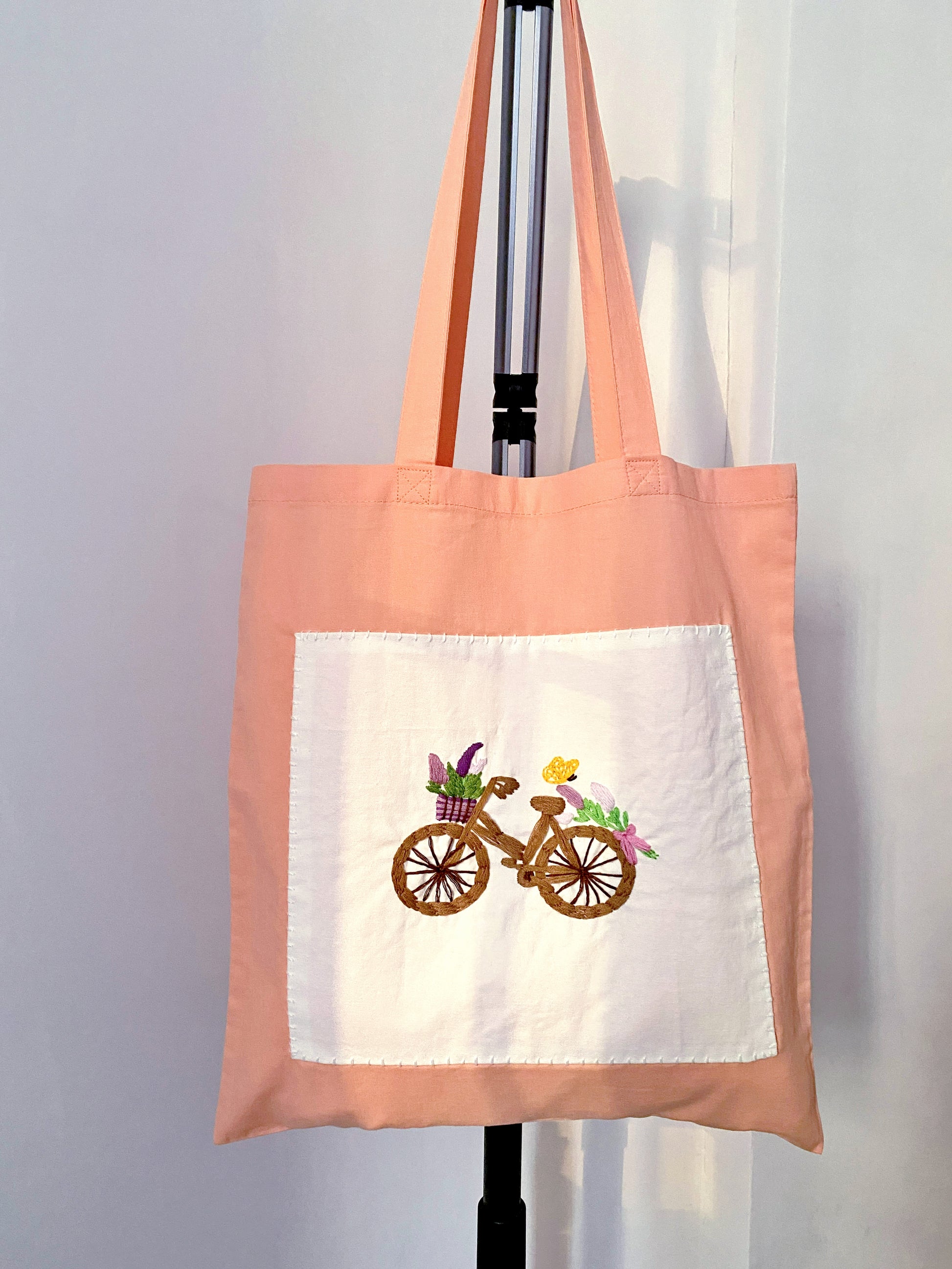 A hand-embroidered sustainable orange tote bag being unwrapped, serving as a thoughtful eco-friendly gift for someone who appreciates slow fashion and artisanal craft.