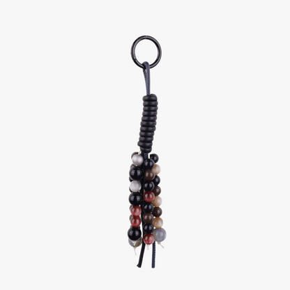 Close up of a vintage natural stone bead bag charm with a tassel hanging from a leather purse handle