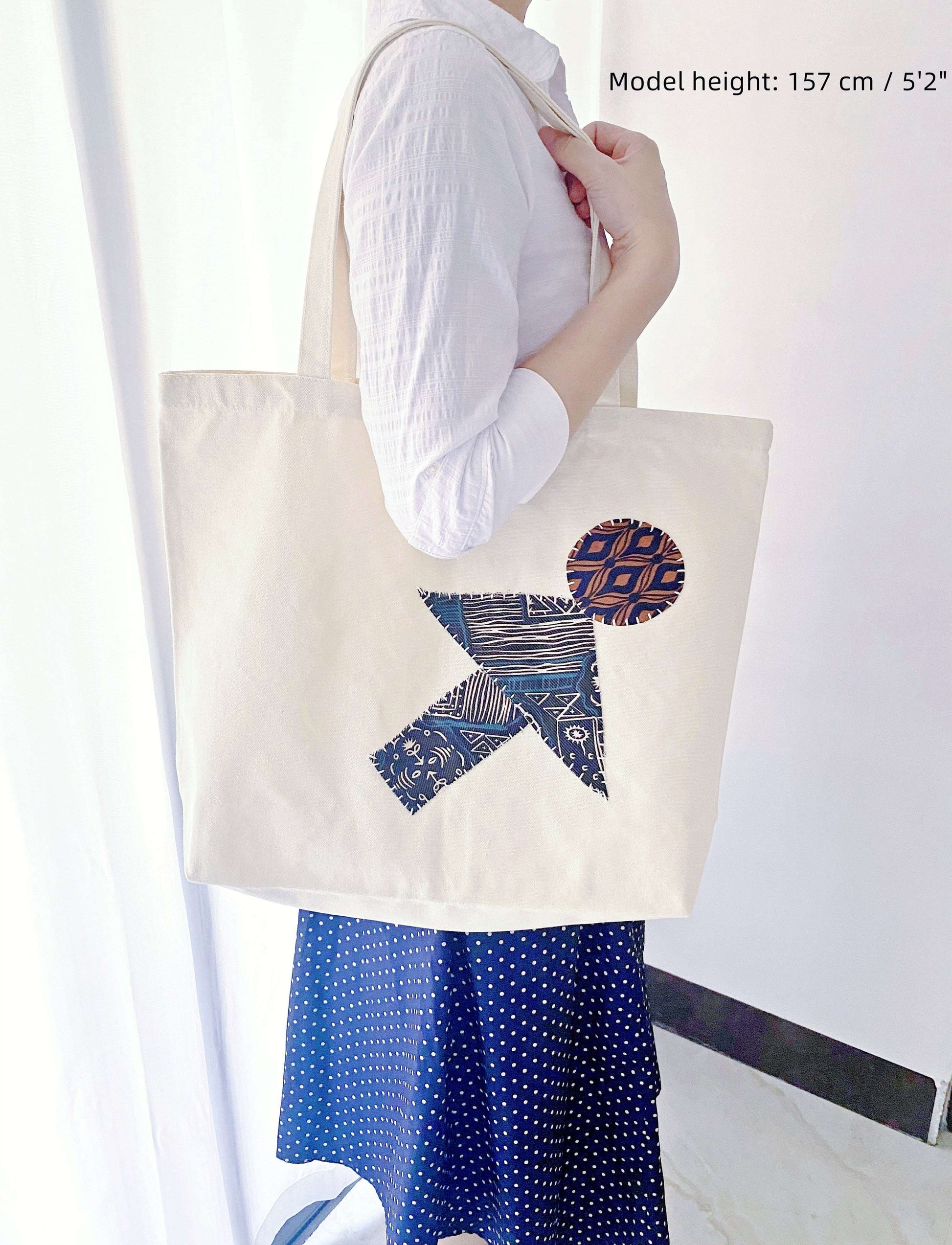 Close-up of sturdy handle stitching on a patchwork bag carrying a heavy laptop and thick art history textbooks, a reliable choice for students avoiding fast fashion.