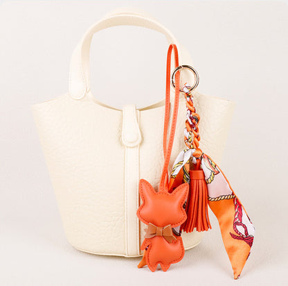 Playful fox pendant hanging from a structured shoulder bag