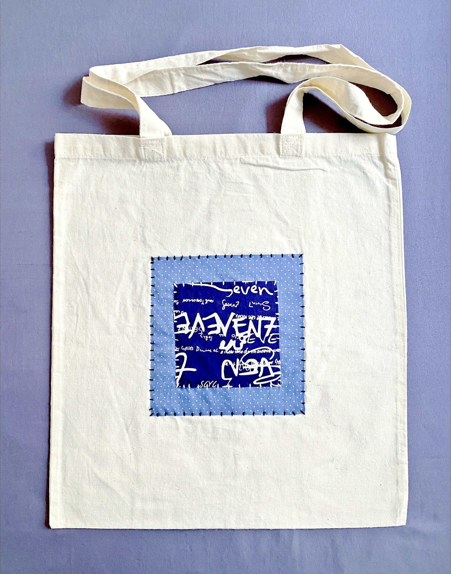 Neutral beige cotton tote bag with handcrafted patchwork detail.