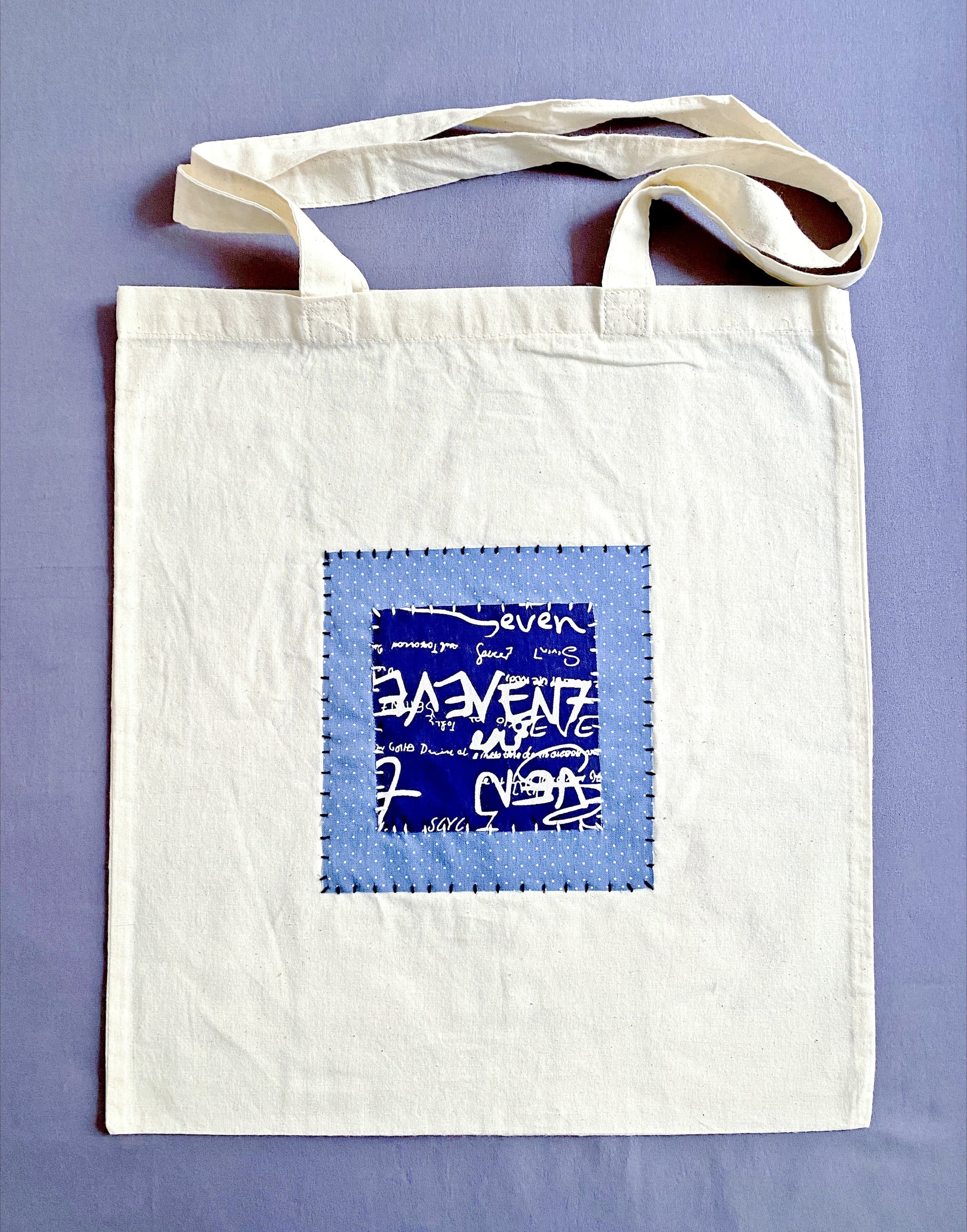 Neutral beige cotton tote bag with handcrafted patchwork detail.