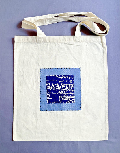 Neutral beige cotton tote bag with handcrafted patchwork detail.