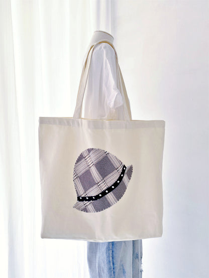 Durable oversized tote featuring handcrafted textile art. Perfectly balances modern utility with a warm, personal human touch.