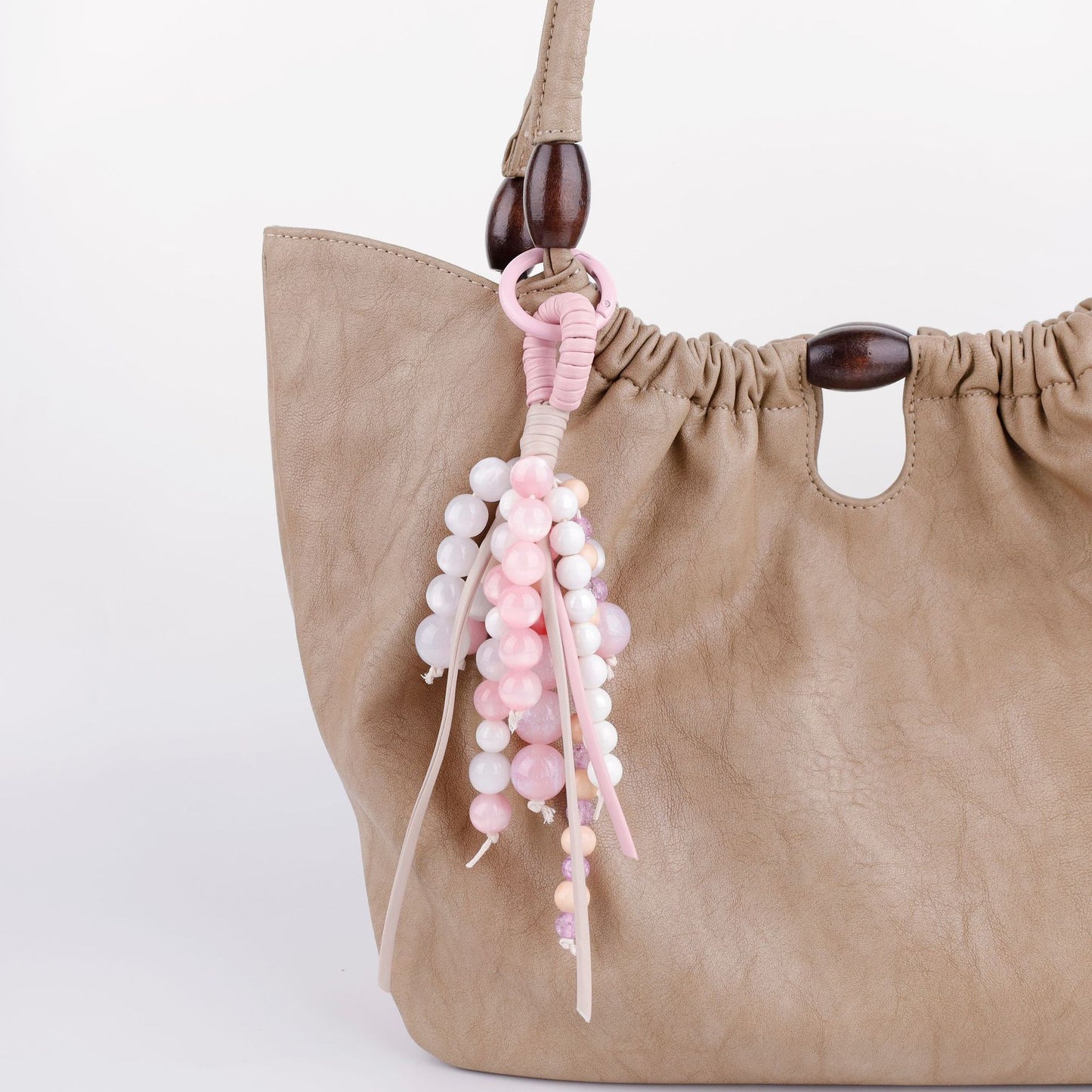 Delicate pink bead charm clipped to a tote bag handle