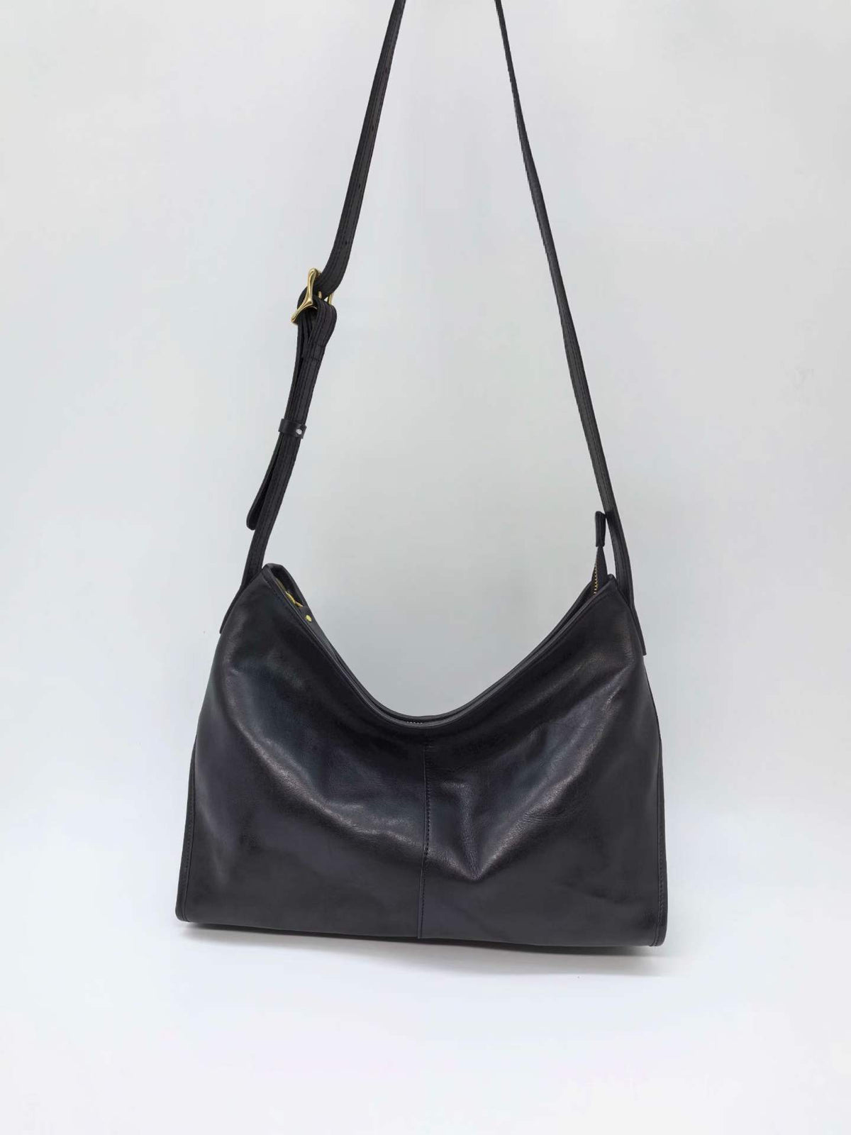 Leather crossbody hobo bag worn on a relaxed weekend walk