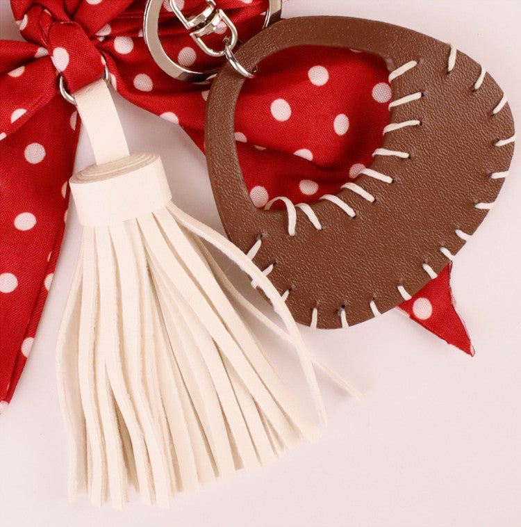 Red scarf bow accessory hanging from a women's handbag
