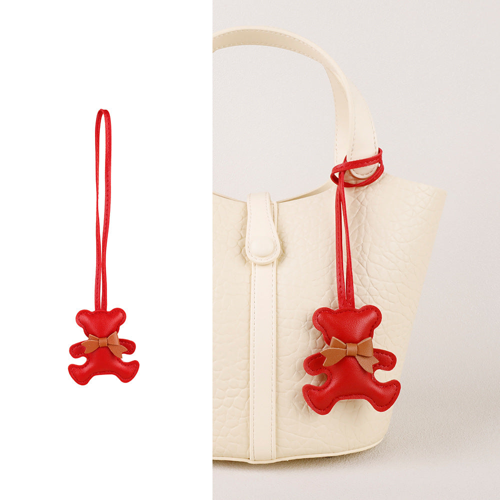 Custom bag accessory detail showing a teddy bear wearing a miniature silk scarf