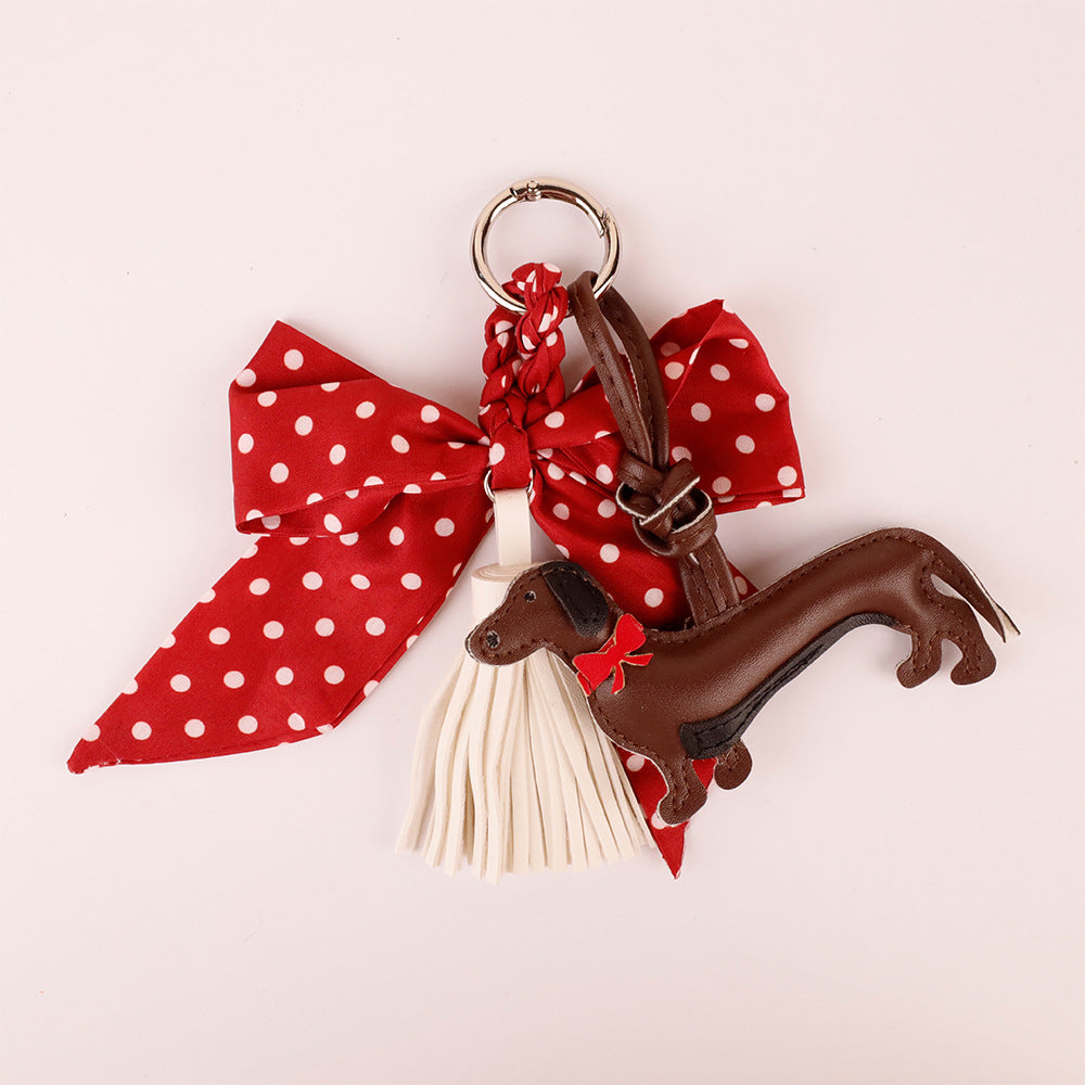 Red bow and tassel charm displayed beside a handbag