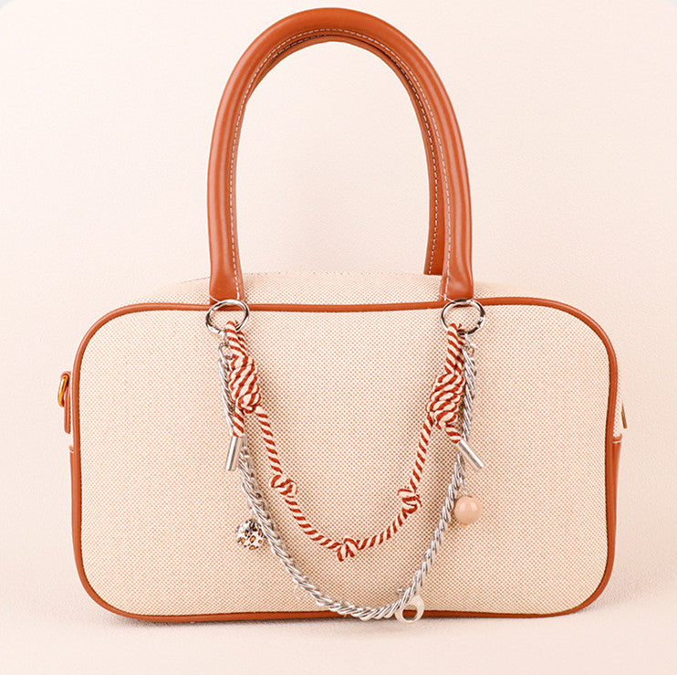 Trendy woven keychain pendant clipped onto a classic shoulder purse handle