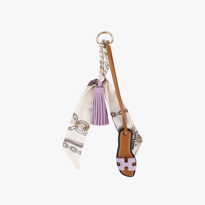 Slipper shaped charm hanging from a leather handbag